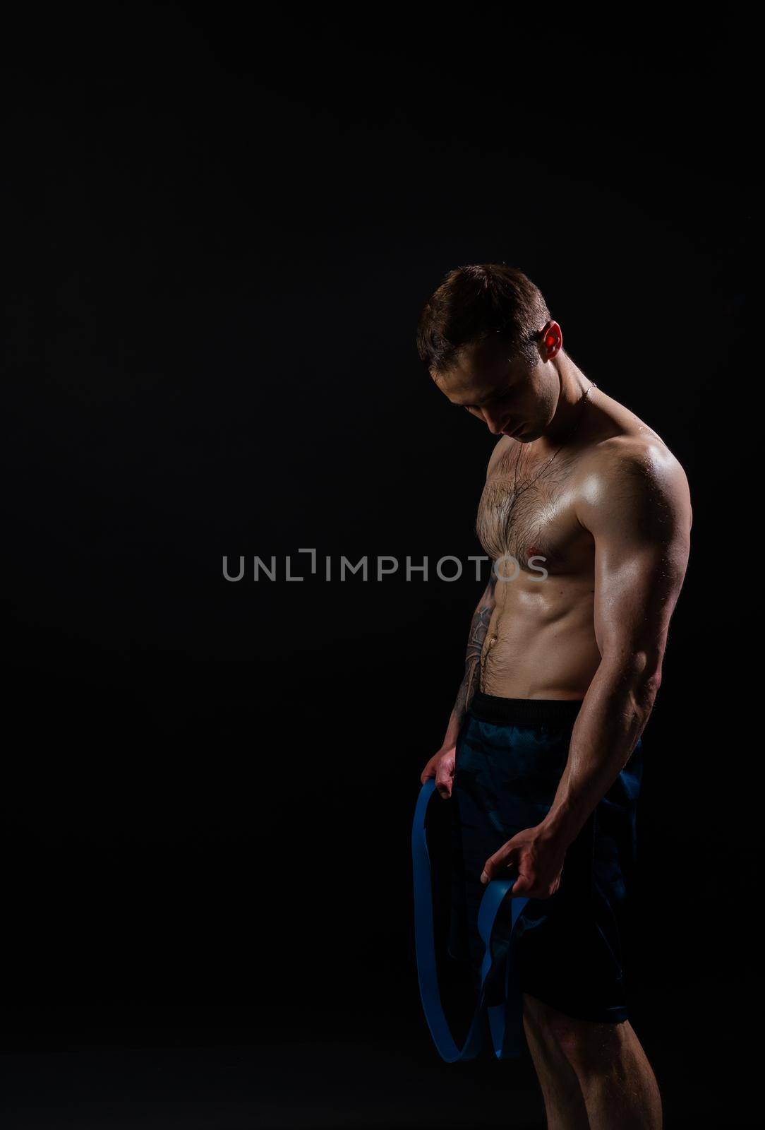 Man on black background keeps dumbbells pumped up in fitness bodybuilding chest torso, athlete training man bodybuilder hand, healthy lifestyle. sportive adult, gym fit With a ribbon in hand, the fitness gum is black