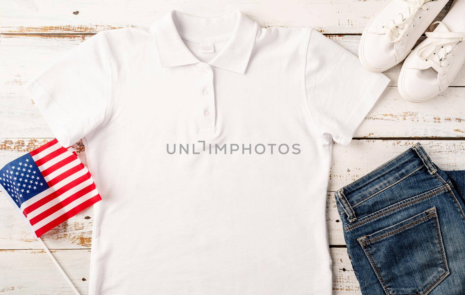 Mockup design white polo t shirt for logo, top view on white wooden background with US flag, shoes and jeans by Desperada