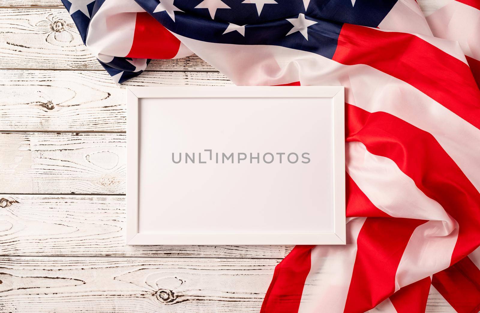 Blank white photo frame for mockup design on American national flag wooden background by Desperada