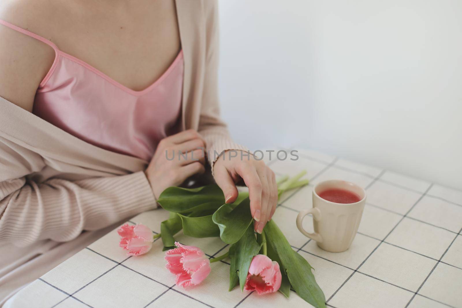 romantic spring portrait of a young woman with tulips at home.