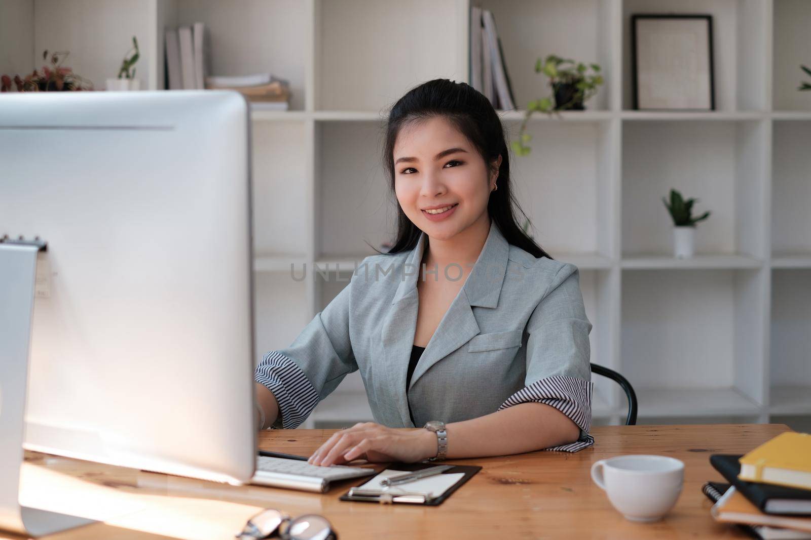 Asian Woman blogger wear blue suit talking with followers, live streaming on social media application. Freelance work from home concept. by itchaznong