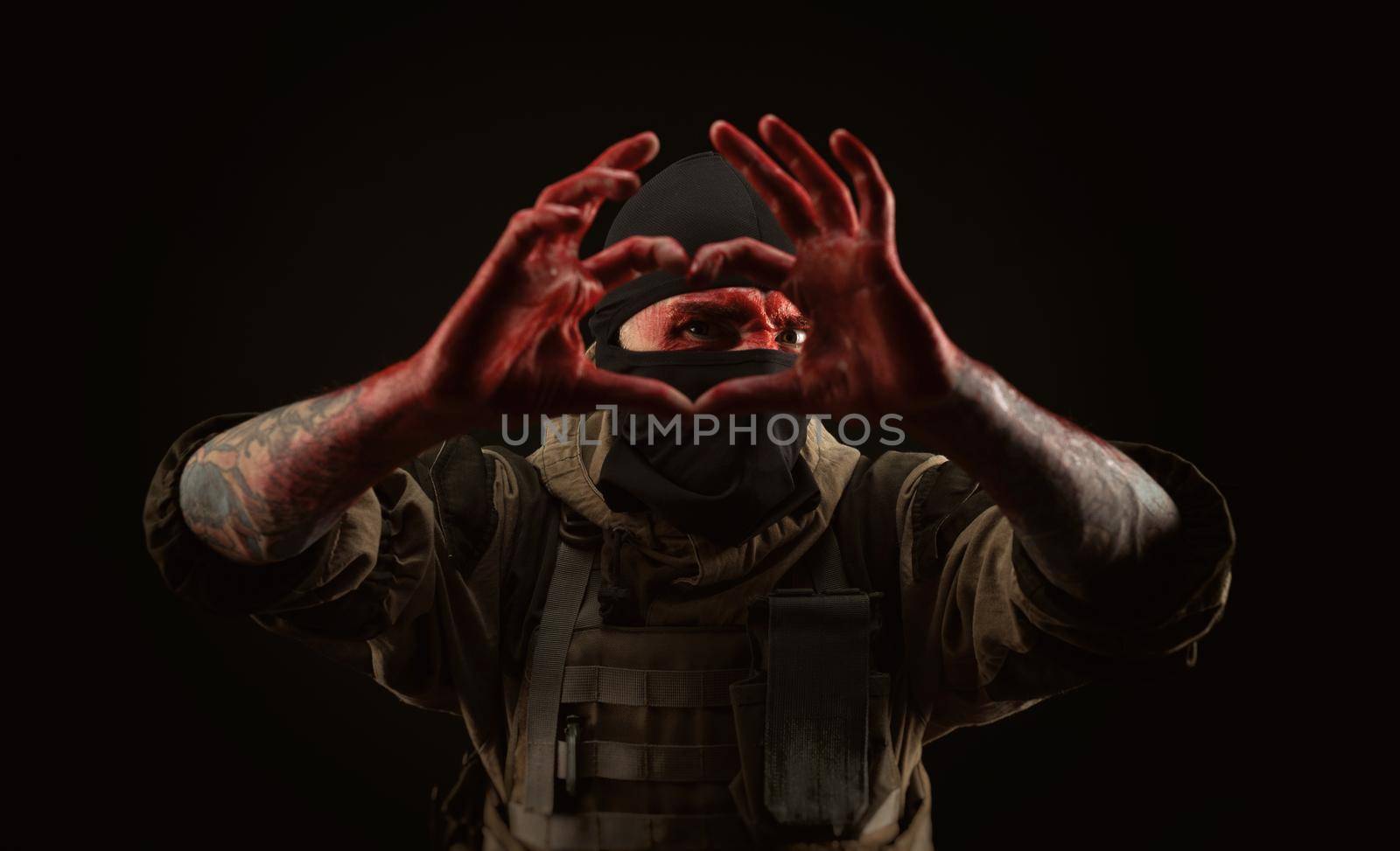 photo of a man in a military uniform and balaclava with a bloody face and hands up to the elbow in blood on a black background by Rotozey