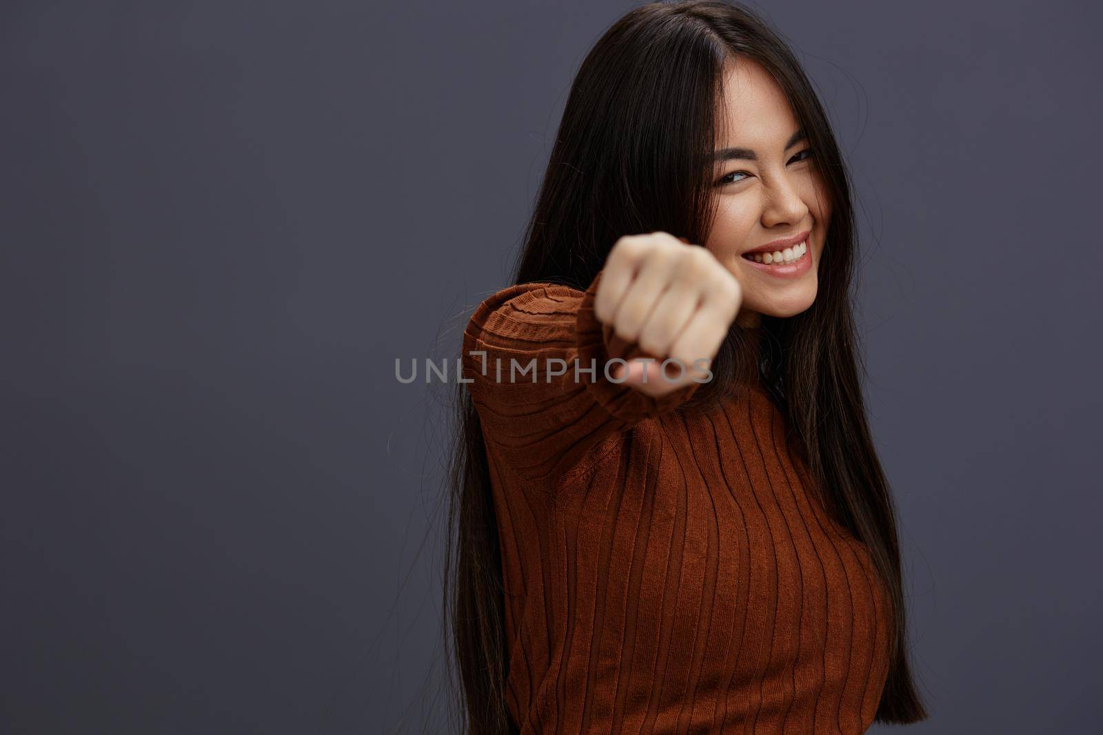young woman hand gestures brown sweater fashion studio model. High quality photo