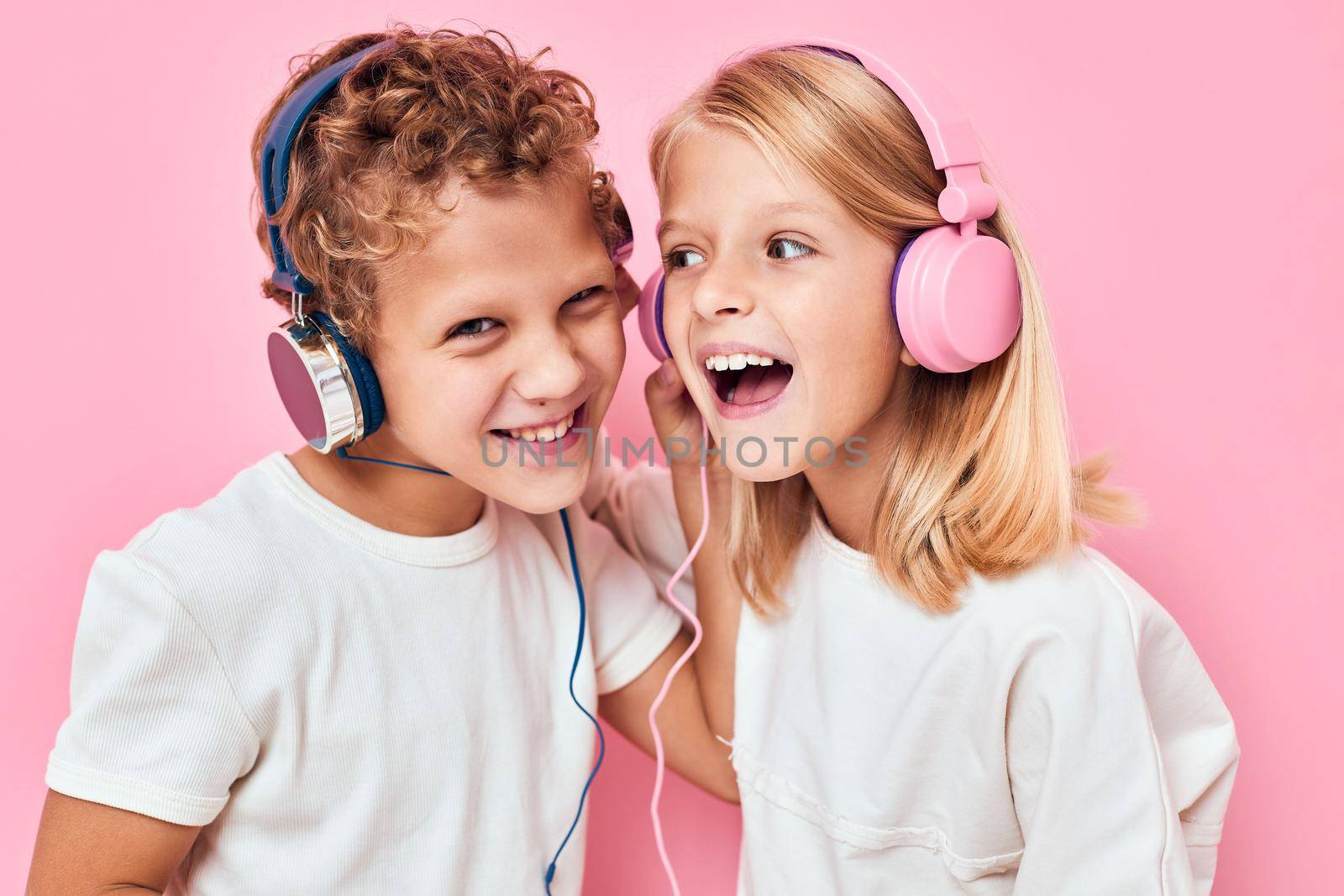 boy and girl stand next to in headphones pink color background by SHOTPRIME