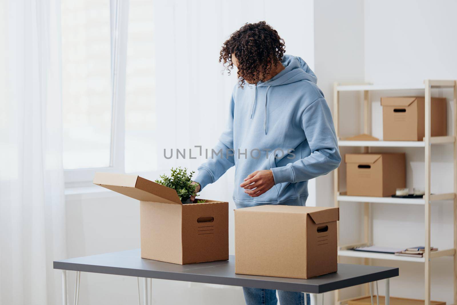 guy with curly hair unpacking things from boxes in the room sorting things out by SHOTPRIME