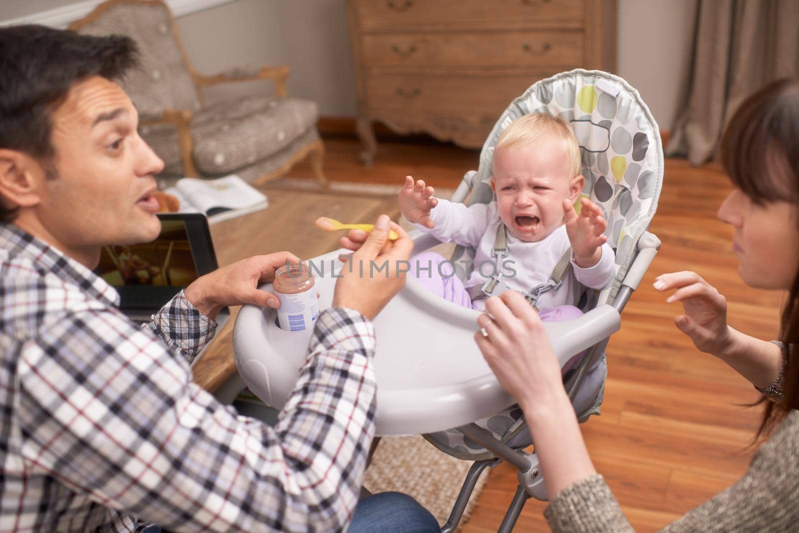 A young father feeding his daughter some baby food.