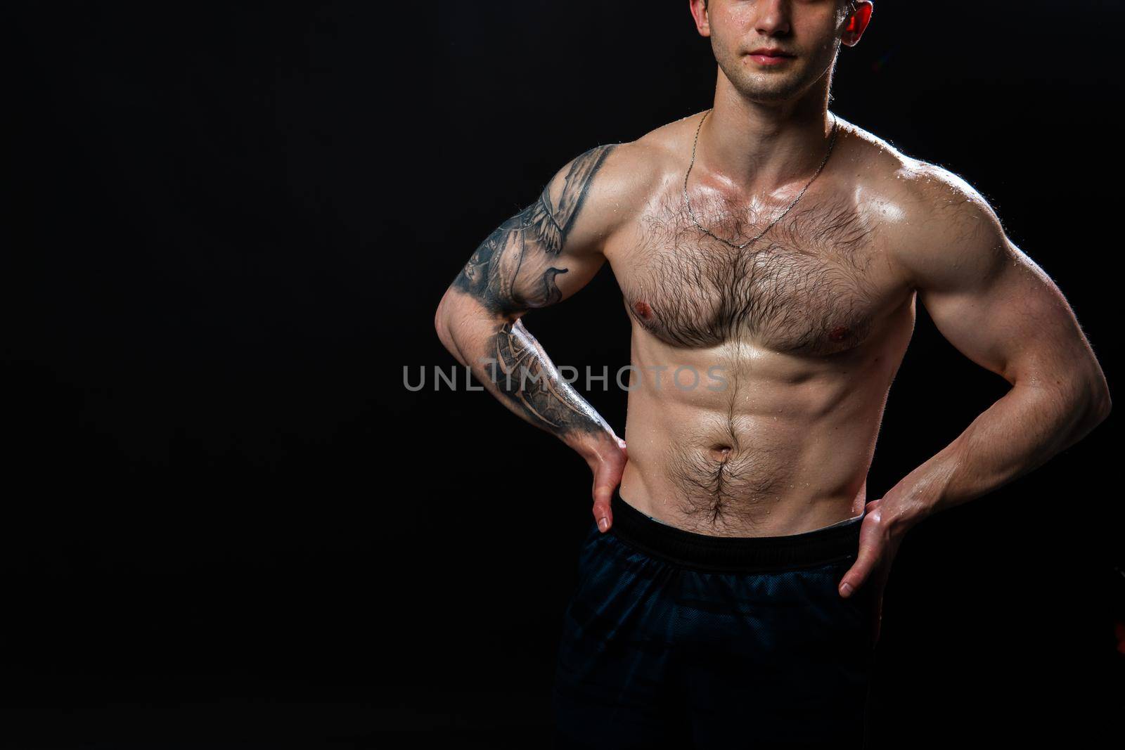 Man on black background keeps dumbbells pumped up in fitness sport, arm muscular exercise dumbbell, person lifestyle. Young sportive adult, guy fit hands behind your back, press tense beautiful body