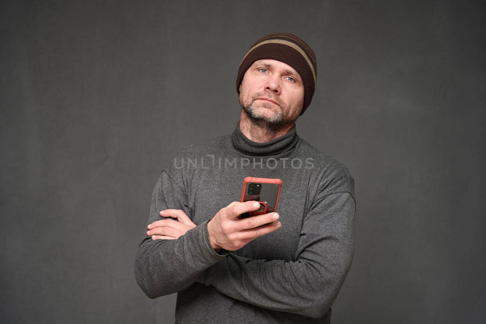 a man with a phone looks into the camera. Portrait on a gray background in the studio