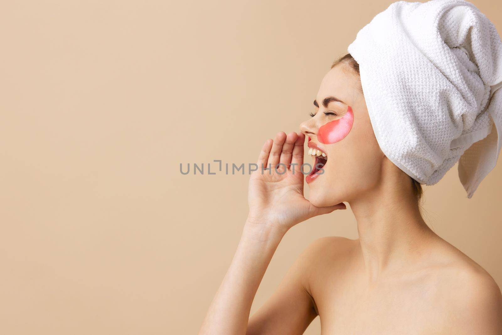 woman pink patches on the face with a towel on the head beige background. High quality photo