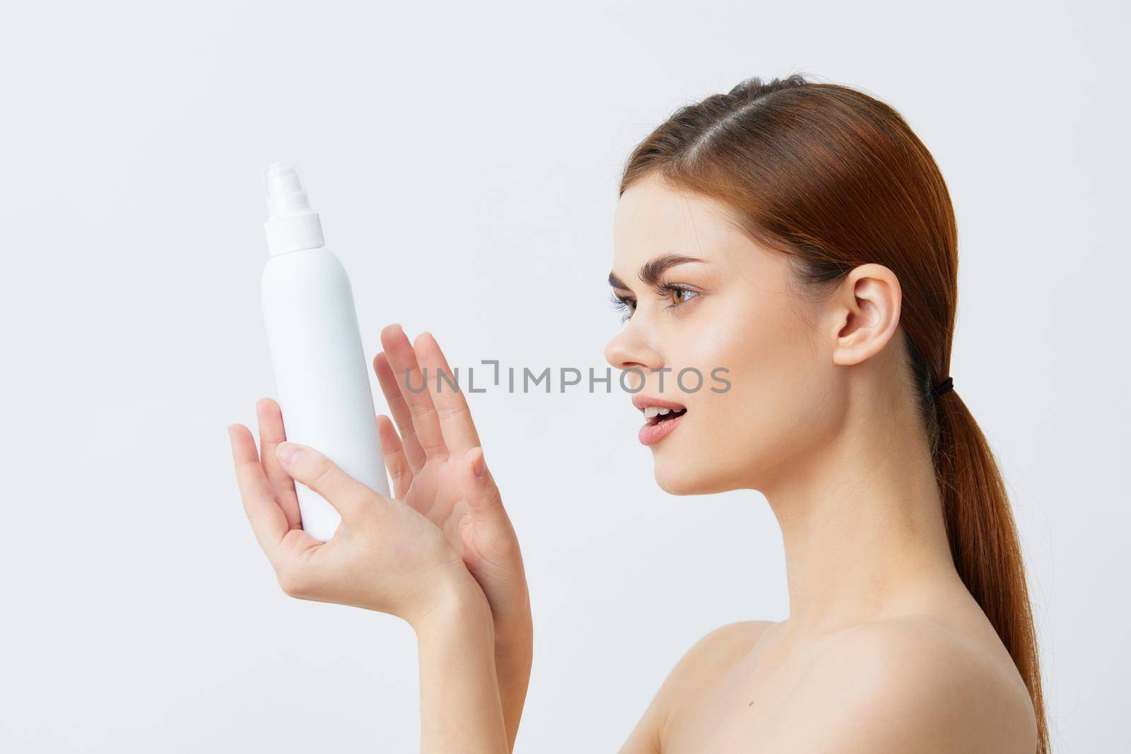 young woman skin care lotion with bare shoulders light background. High quality photo