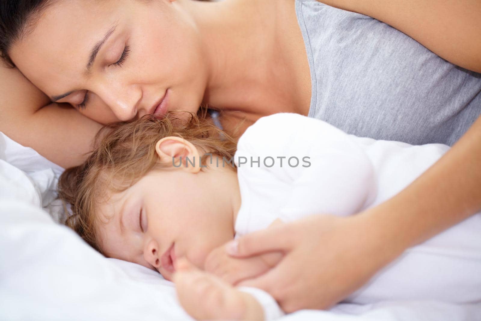 A mother and daughter sleeping on the bed.