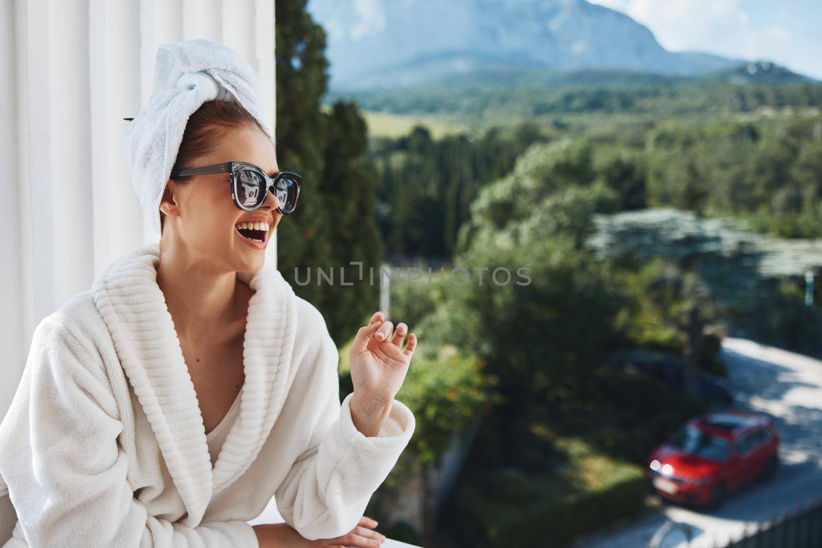 beautiful woman wearing sunglasses posing in a bathrobe on a balcony rest Relaxation concept by SHOTPRIME
