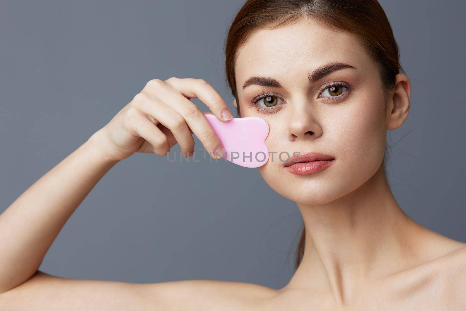 beautiful woman scraper gua sha facial care home facial massage isolated background. High quality photo