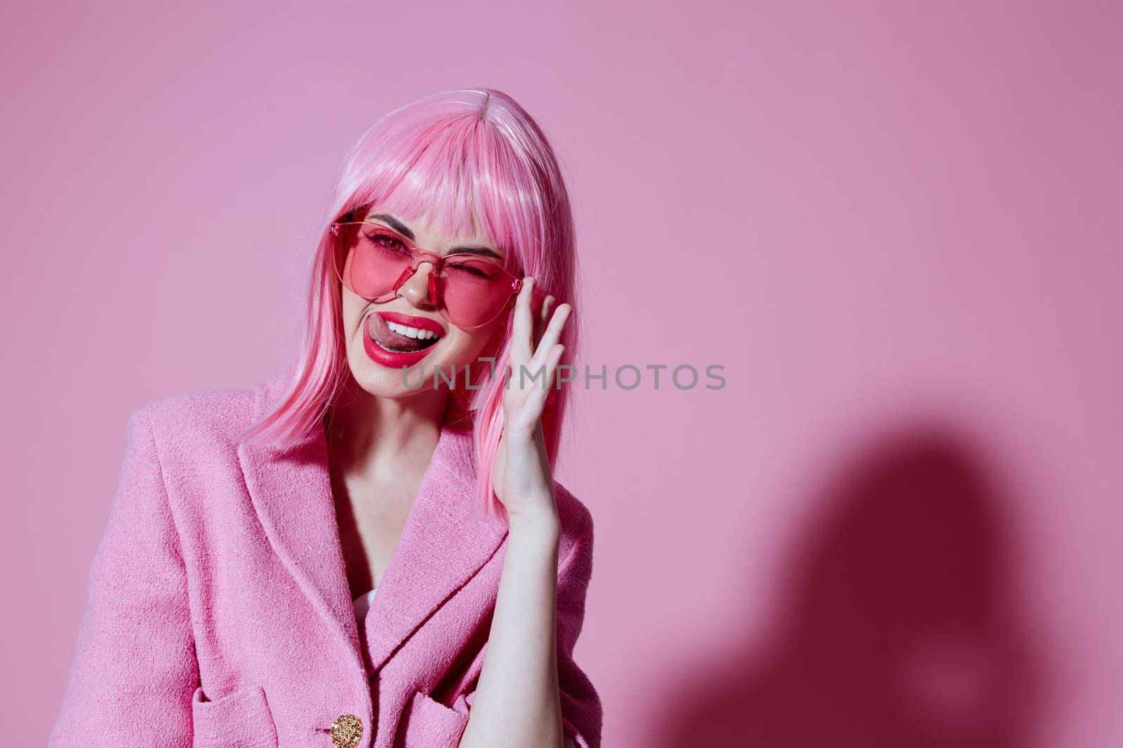 Portrait of a young woman gesturing with hands pink jacket lifestyle glamor pink background unaltered. High quality photo