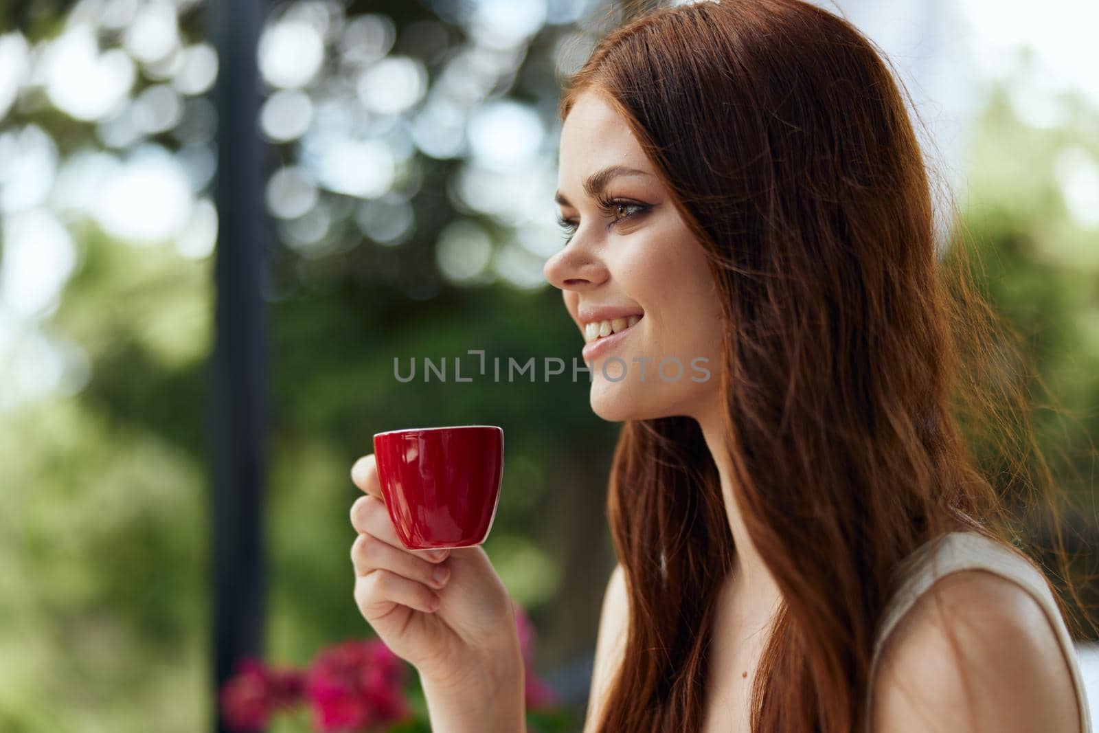 cheerful woman in a white dress drinks coffee outdoors in a cafe unaltered by SHOTPRIME
