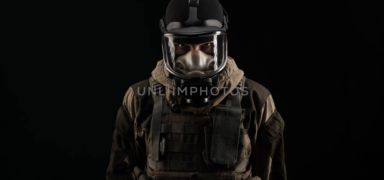 a man in a military uniform and a gas mask holds with an angry expression of emotions on a black background by Rotozey