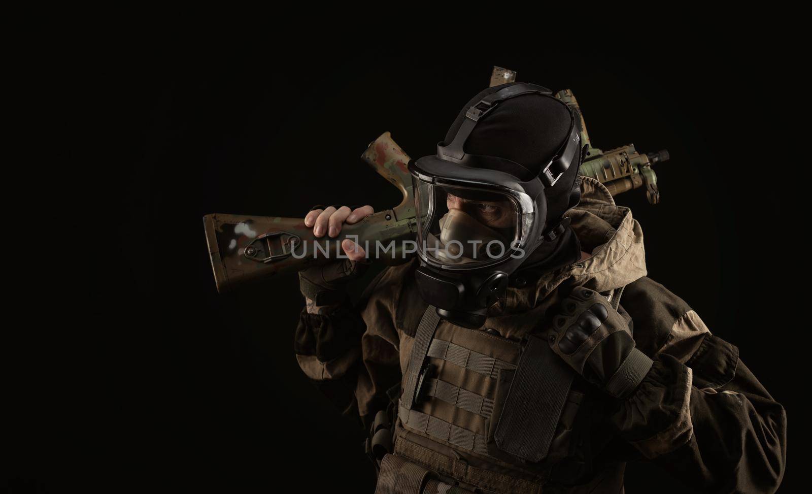 man in a military uniform and a gas mask holds a weapon with an angry expression of emotion