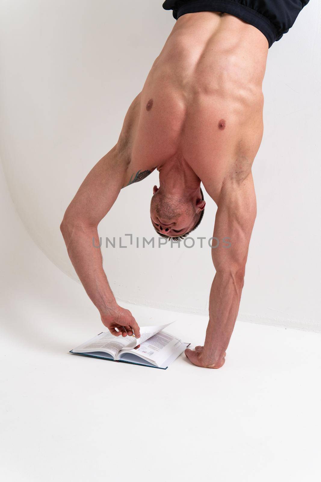Bodybuilder reads the book on a white background isolated at the bottom of his head on his hands handsome macho, athletic fitness reader body healthy, intellectual Smile strength tan