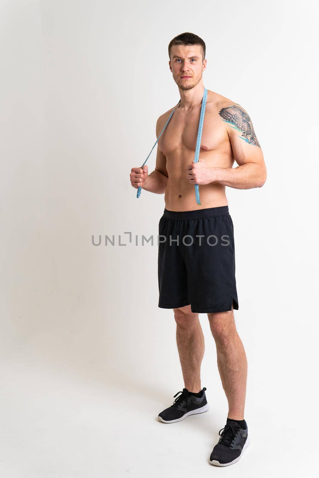 A man measures the waist of a metre and poses against a white background isolated fitness waist, healthy health abdomen lifestyle weight, bodybuilder person. Oss beautiful isolated sport attractive tape