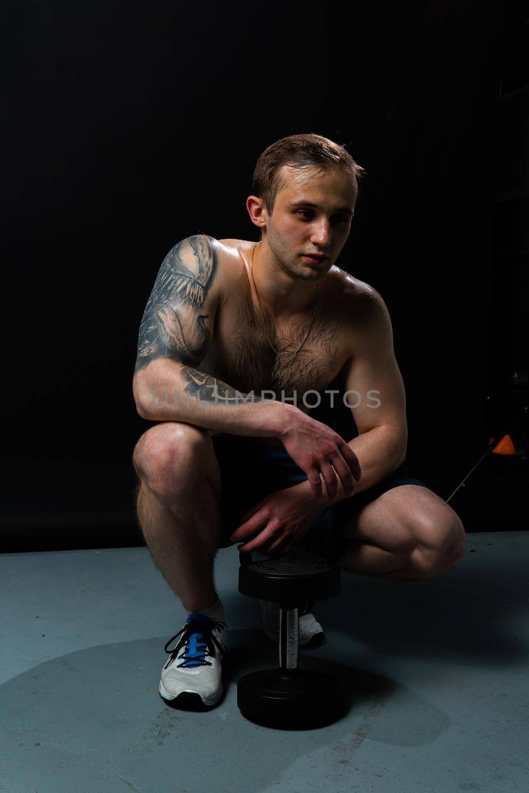 Man on black background keeps dumbbells pumped up in fitness bodybuilding sexy torso, athlete training workout lifting hand, shirtless lifestyle. handsome people fit