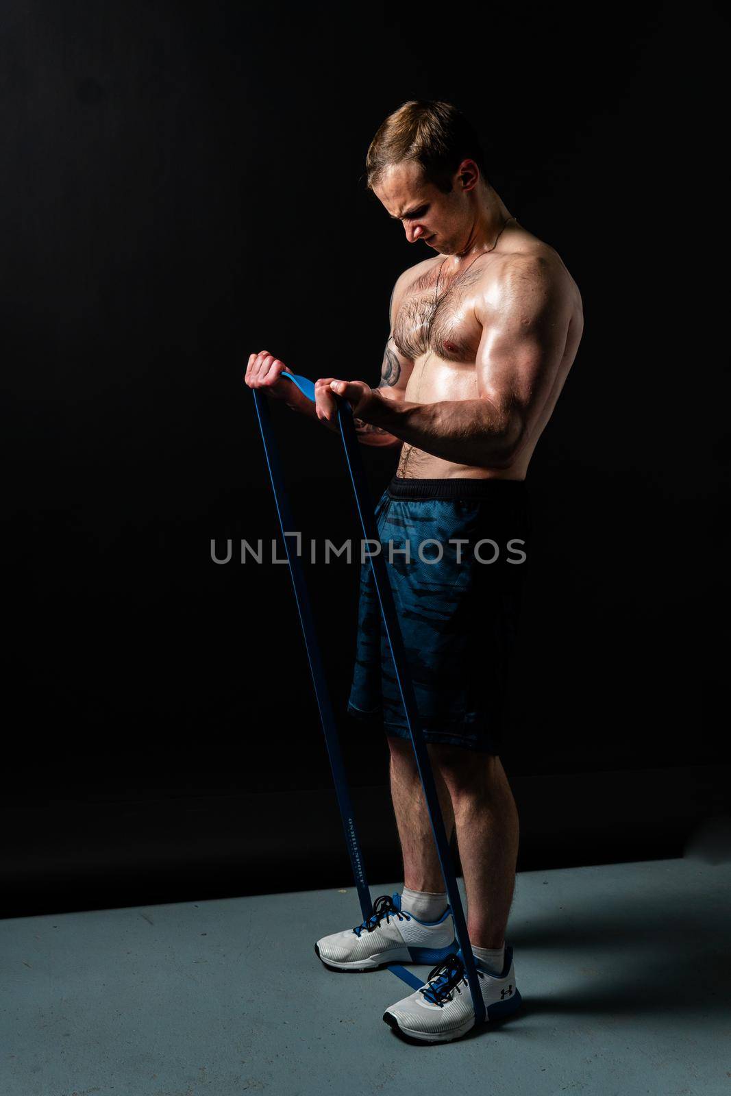 Man on black background keeps dumbbells pumped up in fitness muscle biceps black, workout bodybuilder hand, male lifestyle. Attractive skin power, gym fit With a ribbon in hand, the fitness gum is black