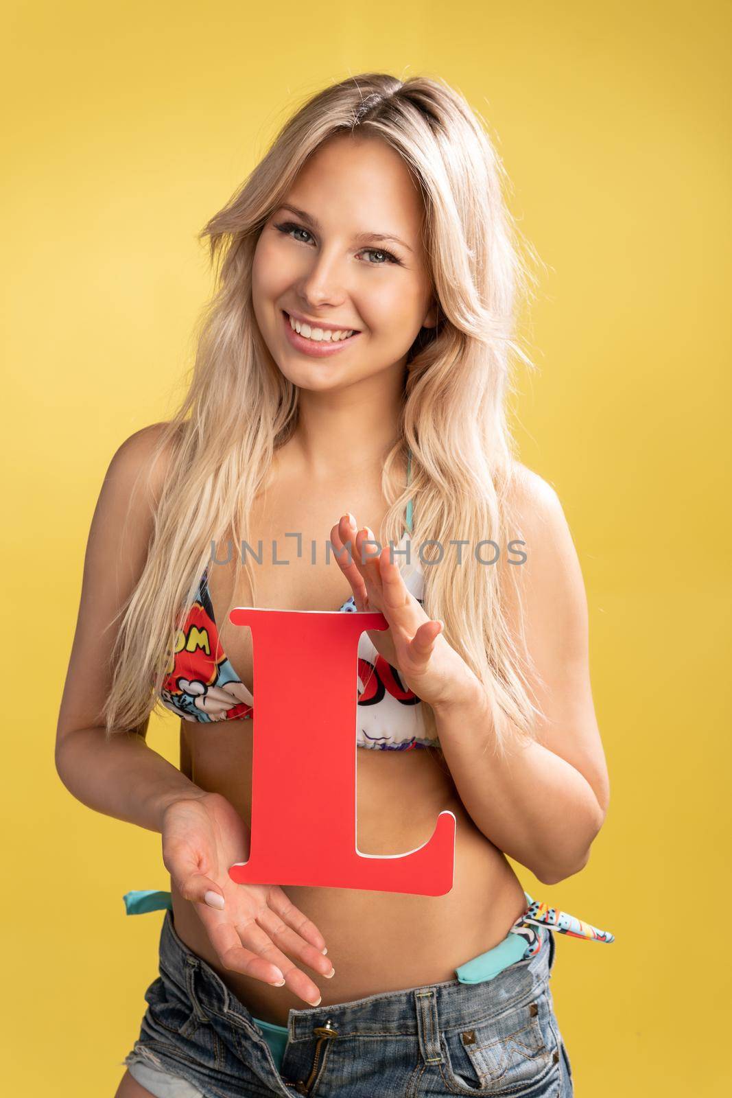 Girl holds the letters of the alphabet word love on a yellow background blonde beautiful smiles caucasian letter, mockup people young studio smile, green. Cute child closeup, copy elementary woman L