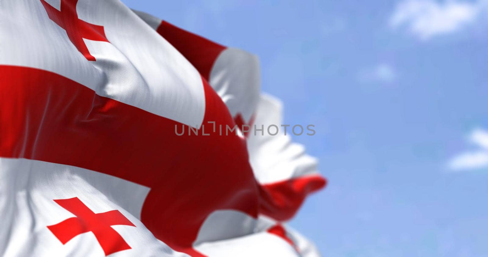 Detail of the national flag of Georgia waving in the wind on a clear day. Georgia is a country located in eastern Europe. Selective focus. Seamless slow motion