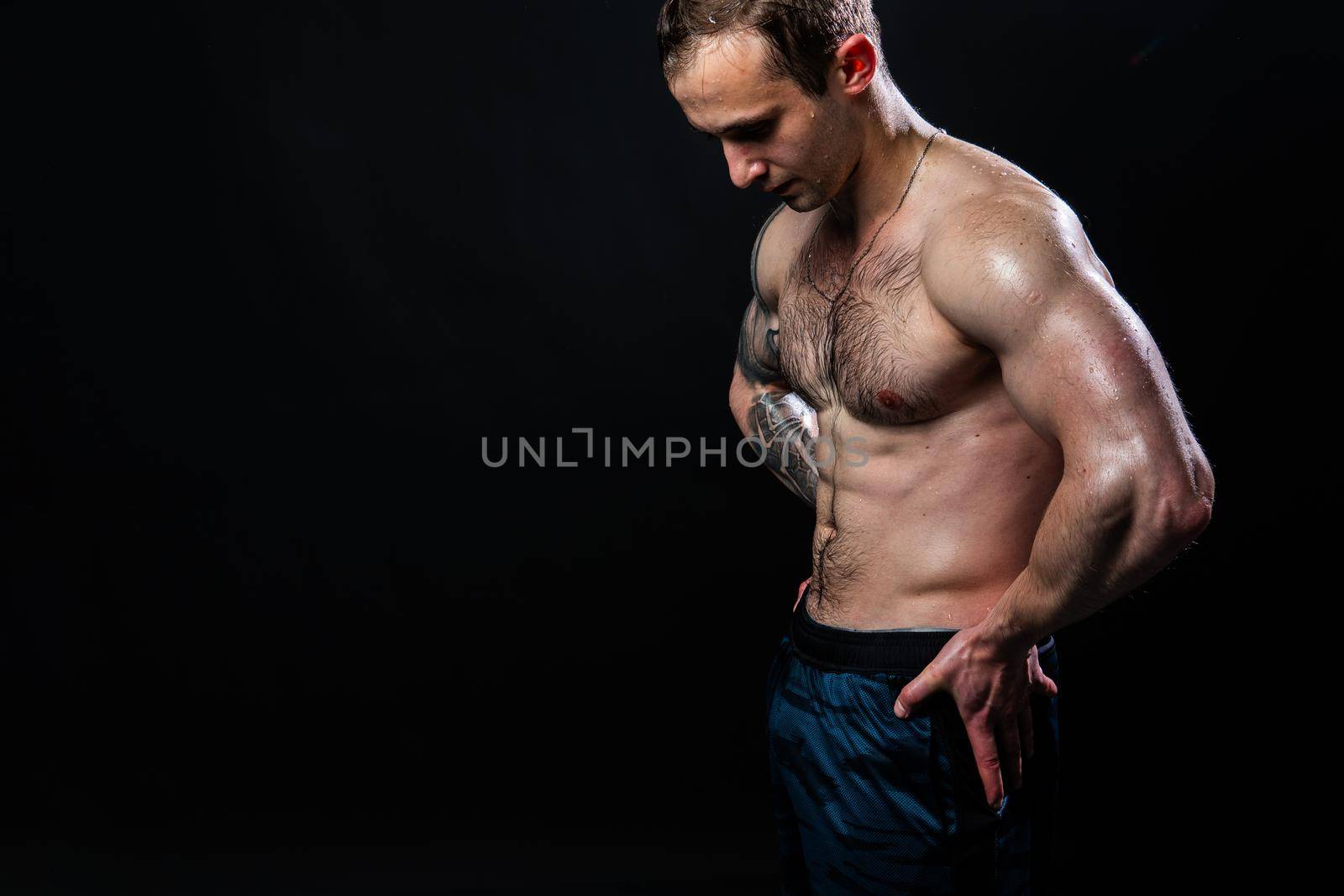 Man on black background keeps dumbbells pumped up in fitness muscle chest sport, man athletic dumbbell, pectoral. handsome adult, gym fit hands behind your back, press tense beautiful body