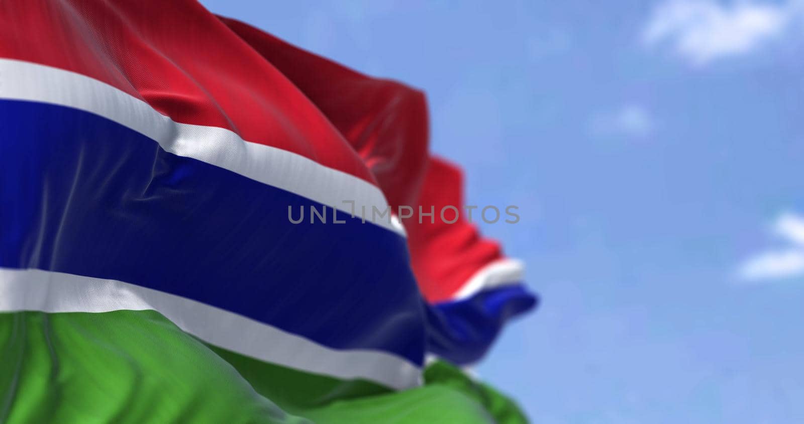Detail of the national flag of Gambia waving in the wind on a clear day. Gambiac iis a country in West Africa. Selective focus. Seamless slow motion