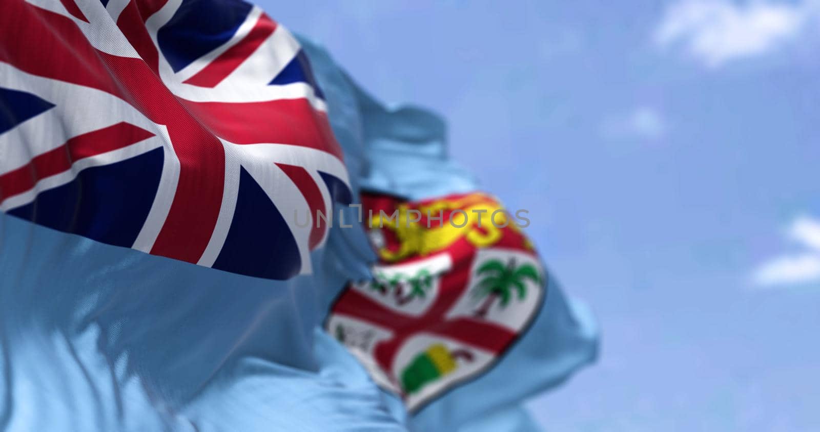 Detail of the national flag of FIji waving in the wind on a clear day. Fiji is an island country in Melanesia, part of Oceania in the South Pacific Ocean. Selective focus. Seamless slow motion