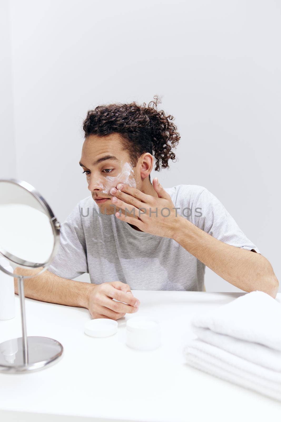 handsome guy sit in front of the mirror, facial skin care light background by SHOTPRIME