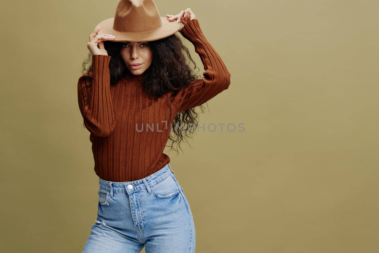 Fashion Seasonal Sale concept. Confident stylish curly Latin female in casual wear, smiling at camera, holding hand on hat, isolated green background. Mock up copy space free place ad. by SHOTPRIME
