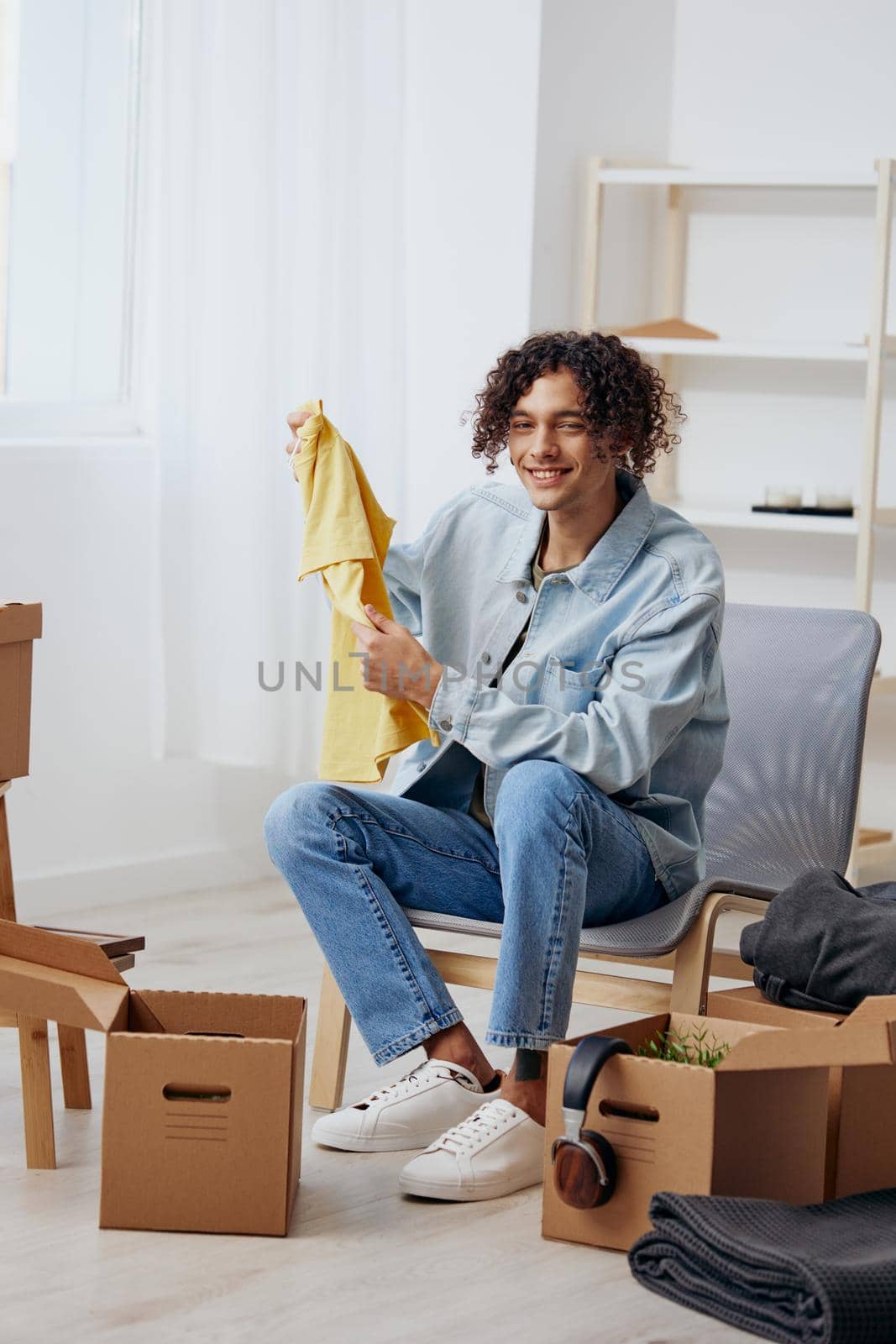 A young man sitting on a chair with boxes interior moving. High quality photo