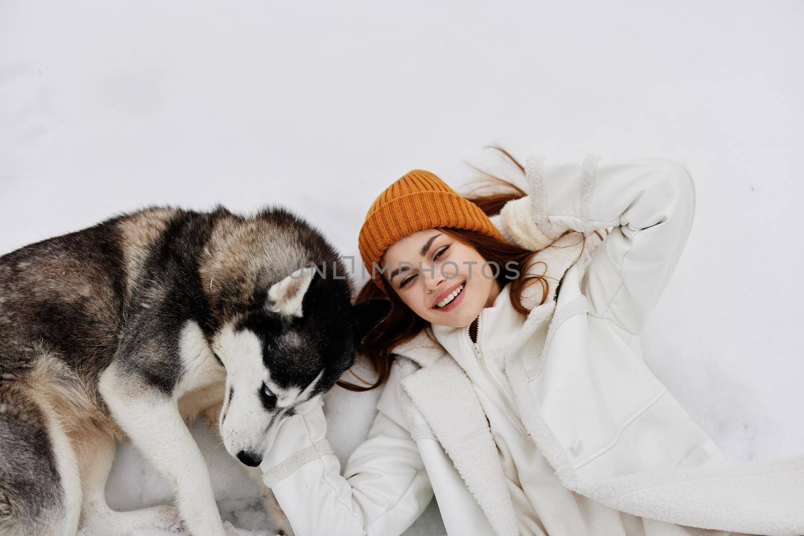 cheerful woman in the snow playing with a dog fun friendship Lifestyle. High quality photo