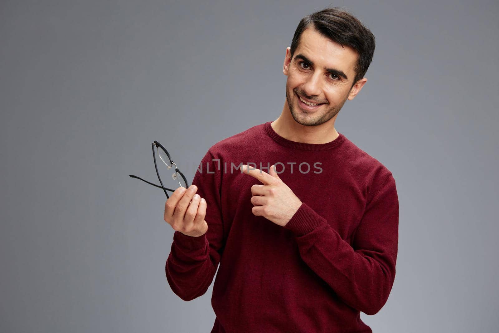 manager pointing to glasses with a smile posing gesture with hands red sweater. High quality photo