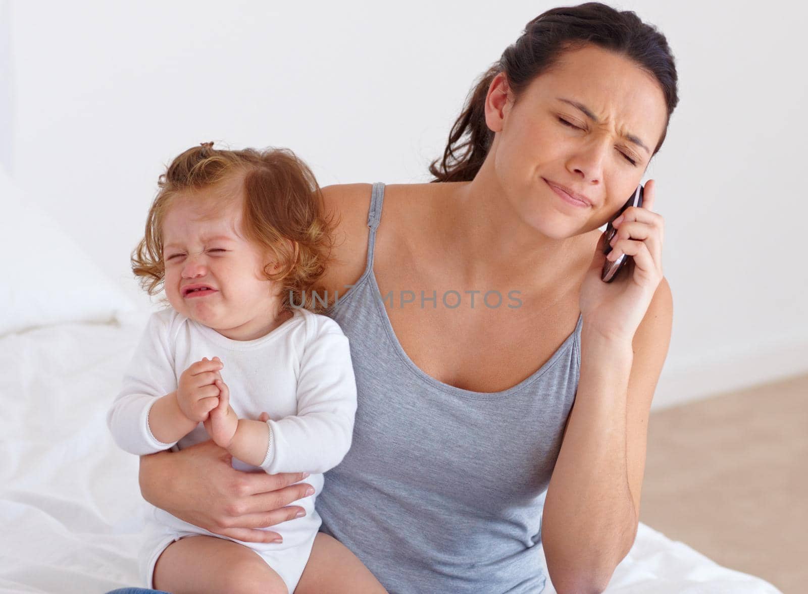 A mother trying to have a phone conversation while her baby is crying in the background.