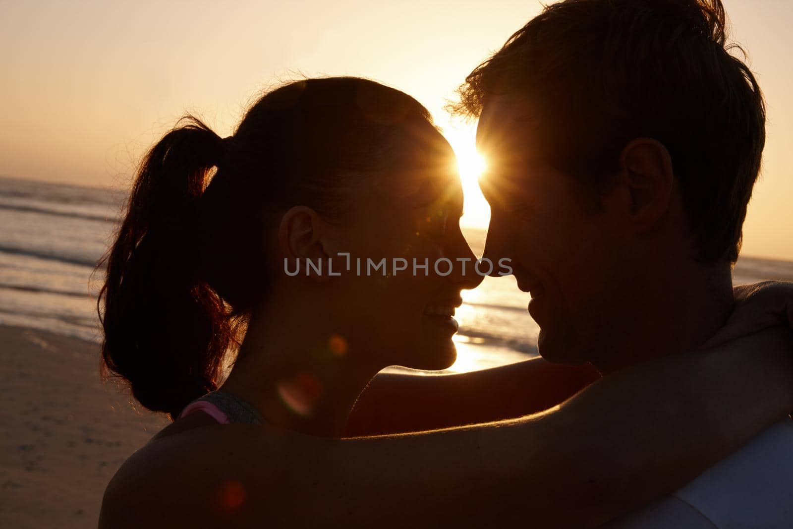 Silhouette of a couple being romantic at the beach at sunset.