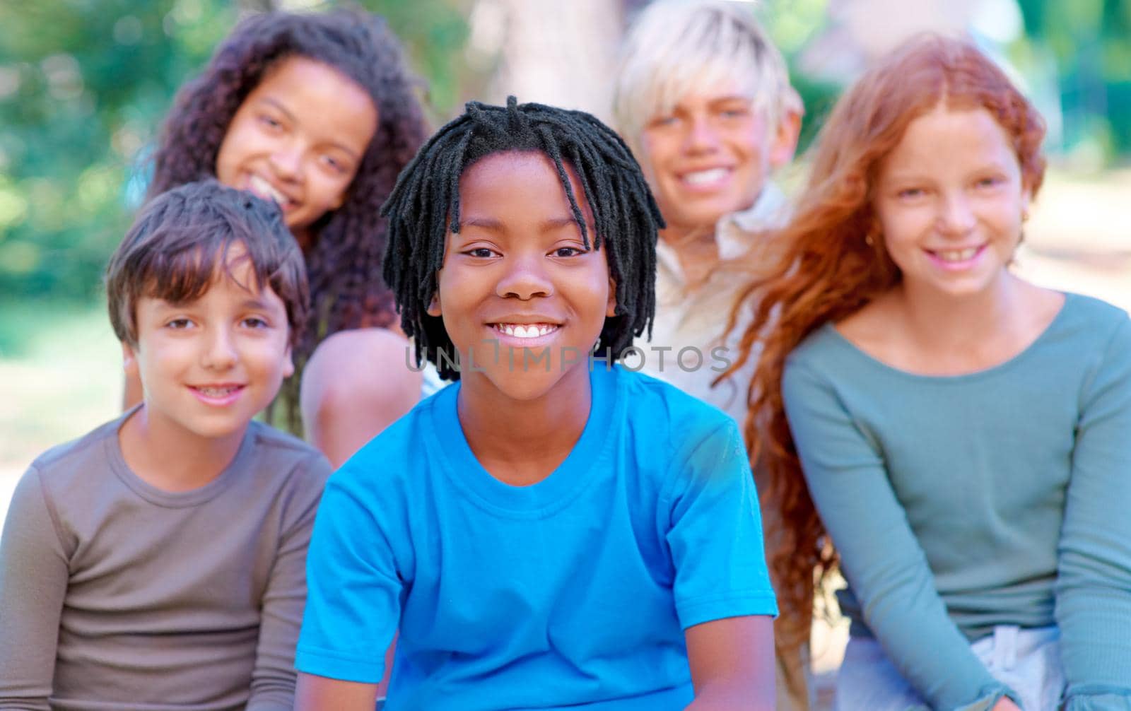A group of children smiling at the camera in the outdoors.