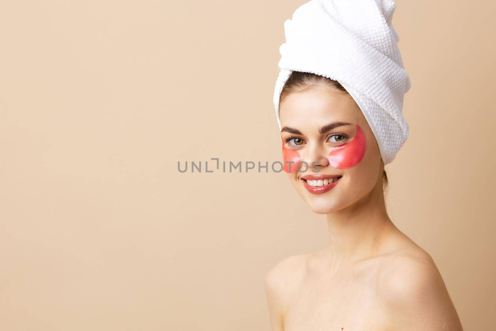 beautiful woman with a towel on his head gesturing with his hands skin care beige background. High quality photo