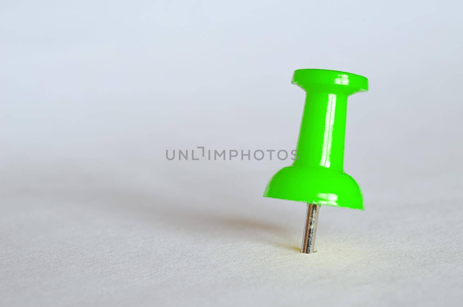 Green push pin. Closeup photography of green thumbtack.
