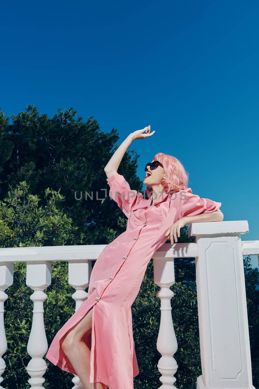 attractive woman with pink hair wearing sunglasses posing sunny day. High quality photo