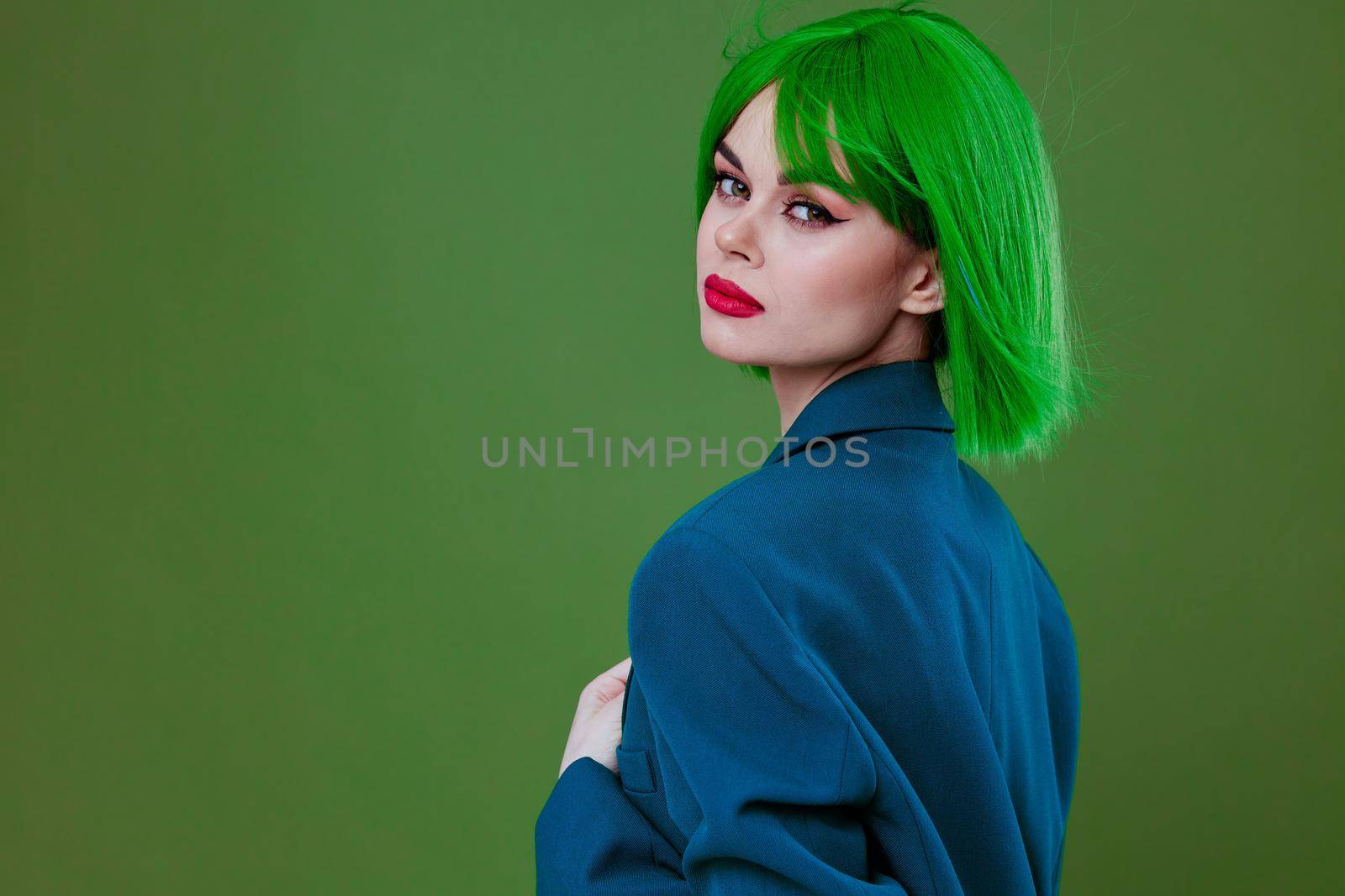 Beauty Fashion woman wearing a green wig blue jacket posing green background unaltered. High quality photo