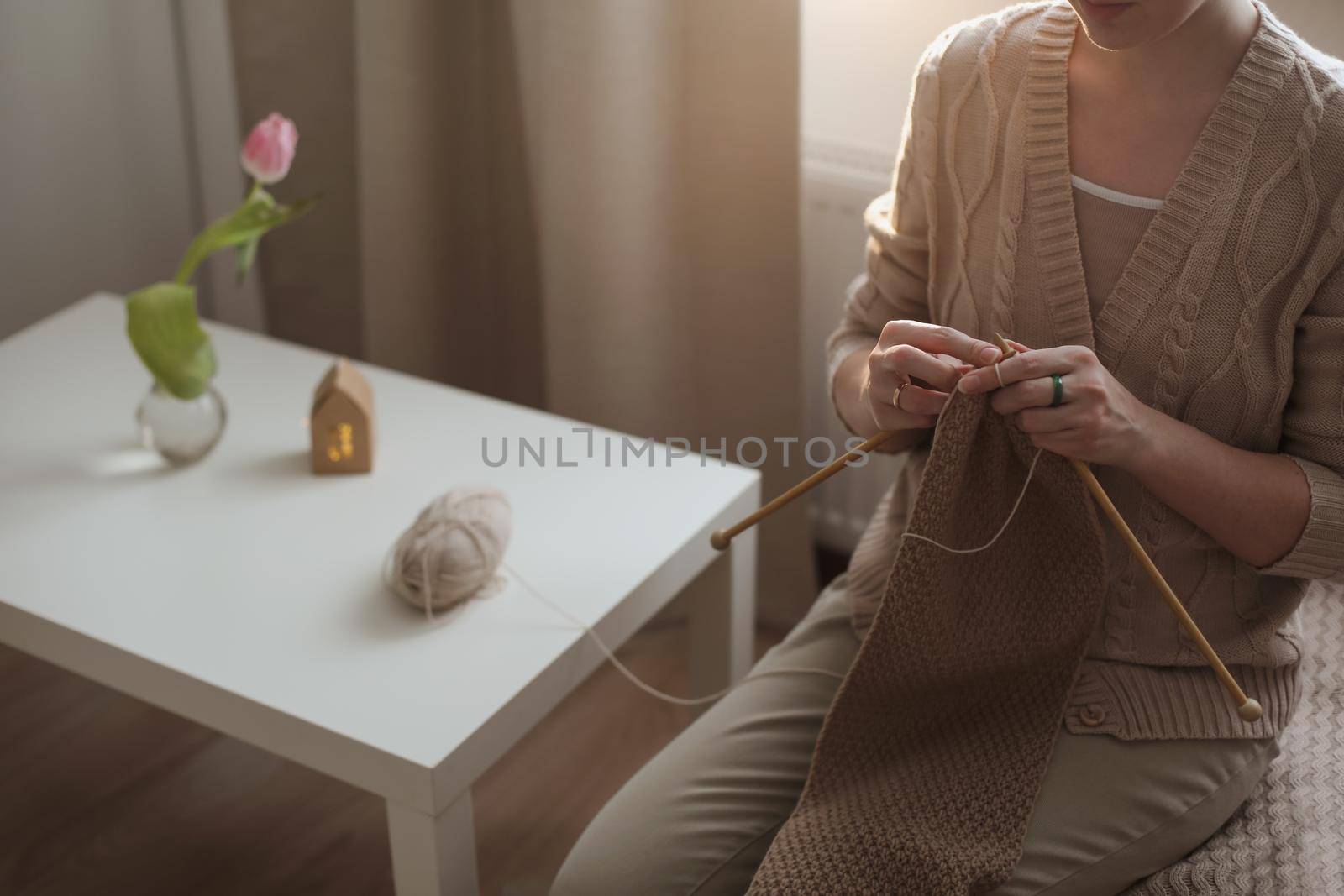 Women's hands knitting from woolen beige yarn
