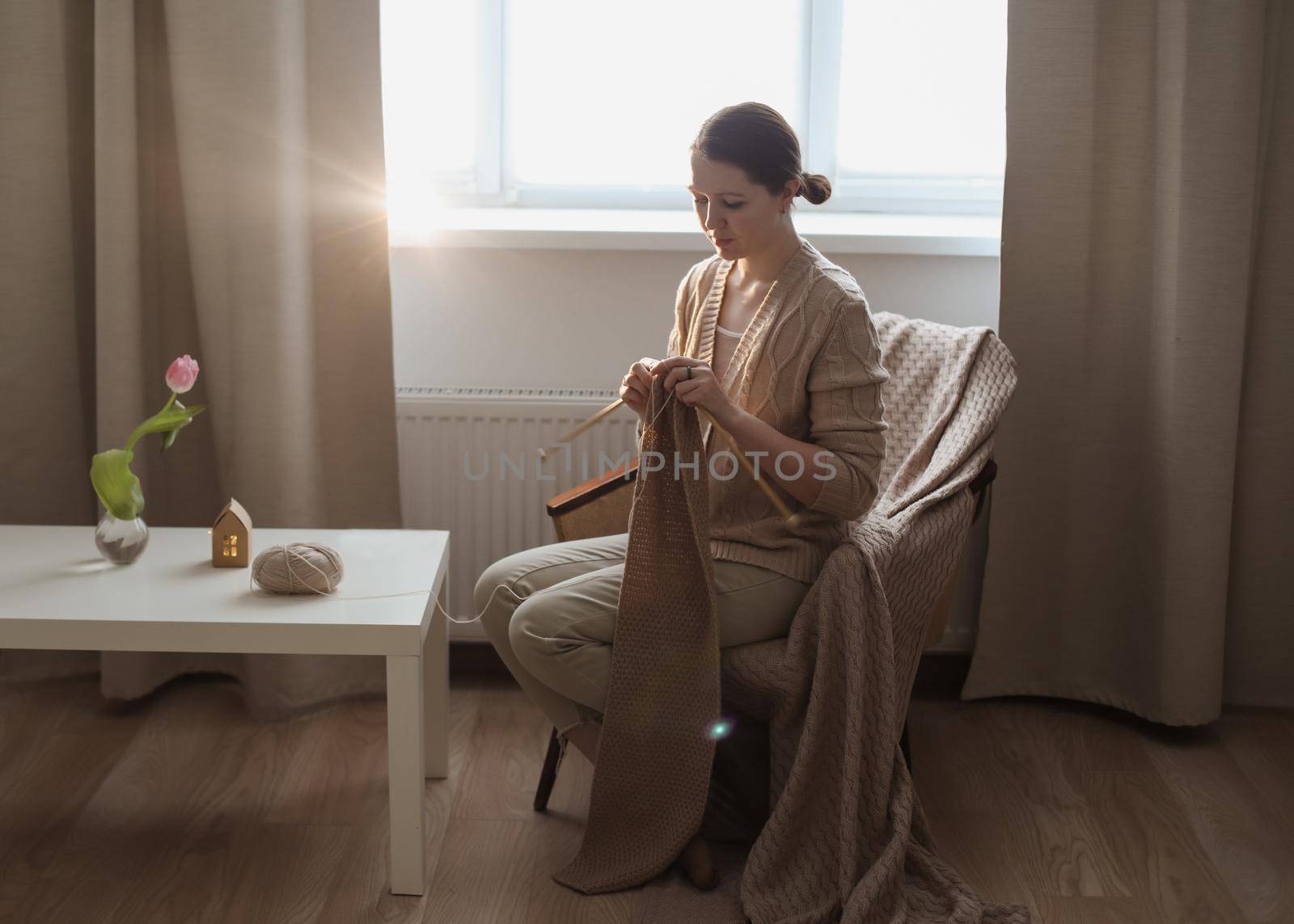 Young woman knitting in a cozy room at home.