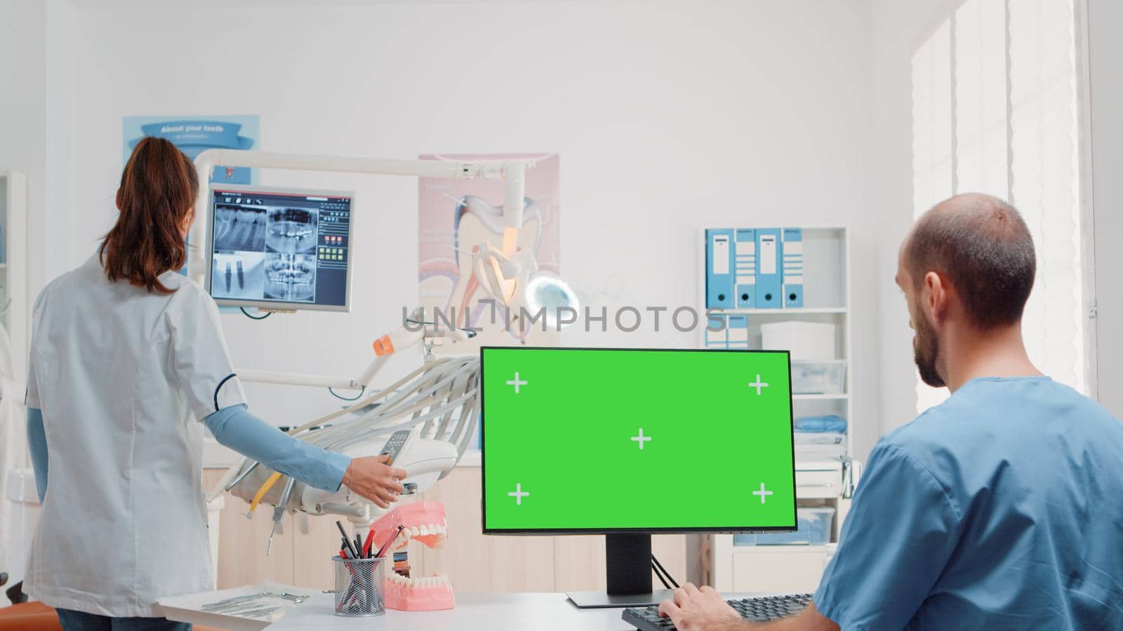 Dental assistant using monitor with horizontal green screen by DCStudio