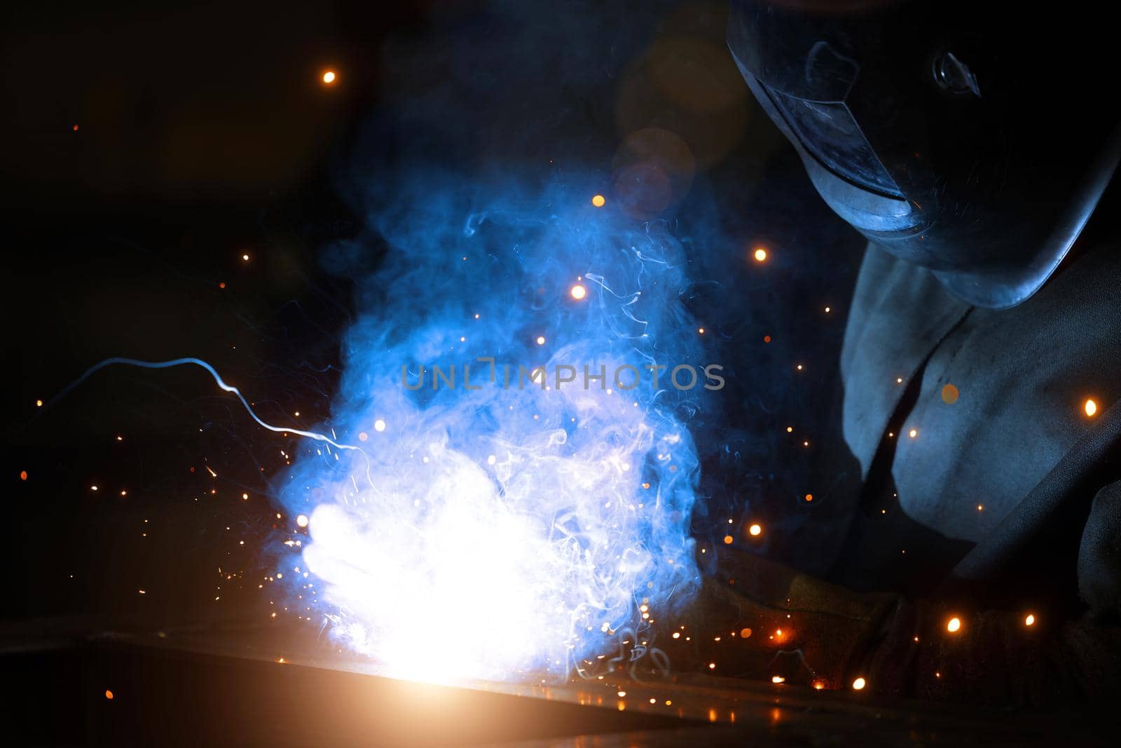 Welder at work. Welding of metal sparks and smoke in the workshop. Industrial Welder With gas Torch in Protective Helmet, welding metal profiles. The welding operation at construction site by EvgeniyQW