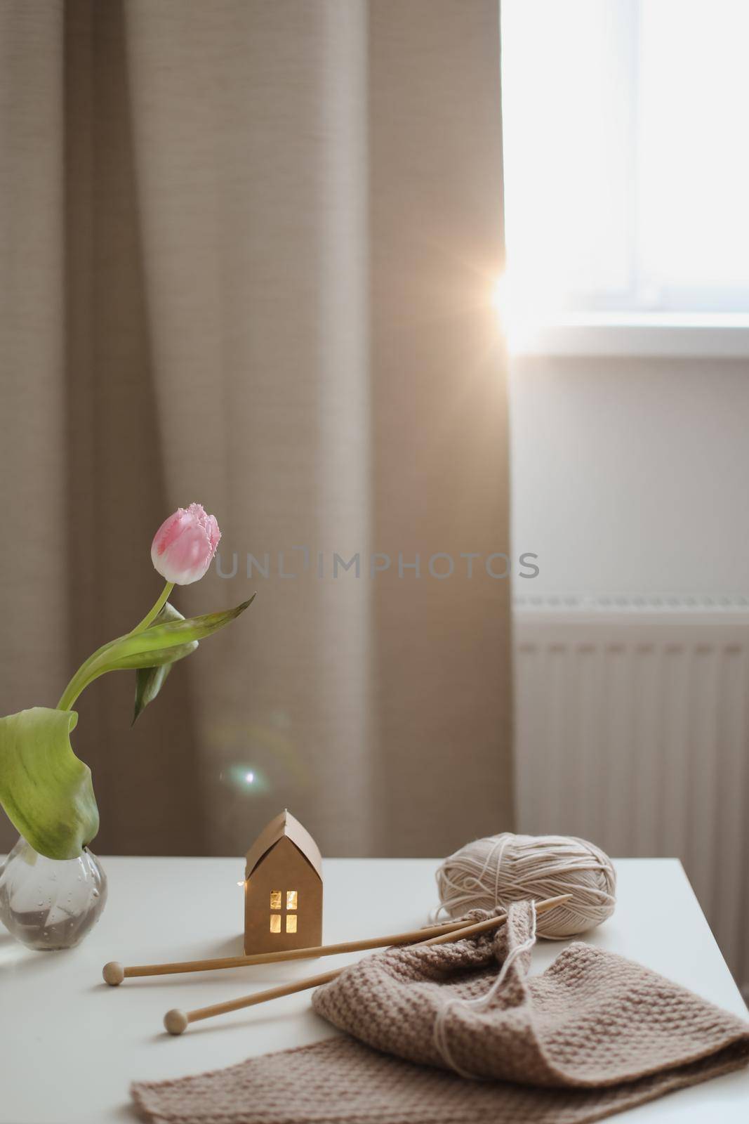 cozy home interior decor with a chair, plaid, table and knitting needles with threads, beige yarn.