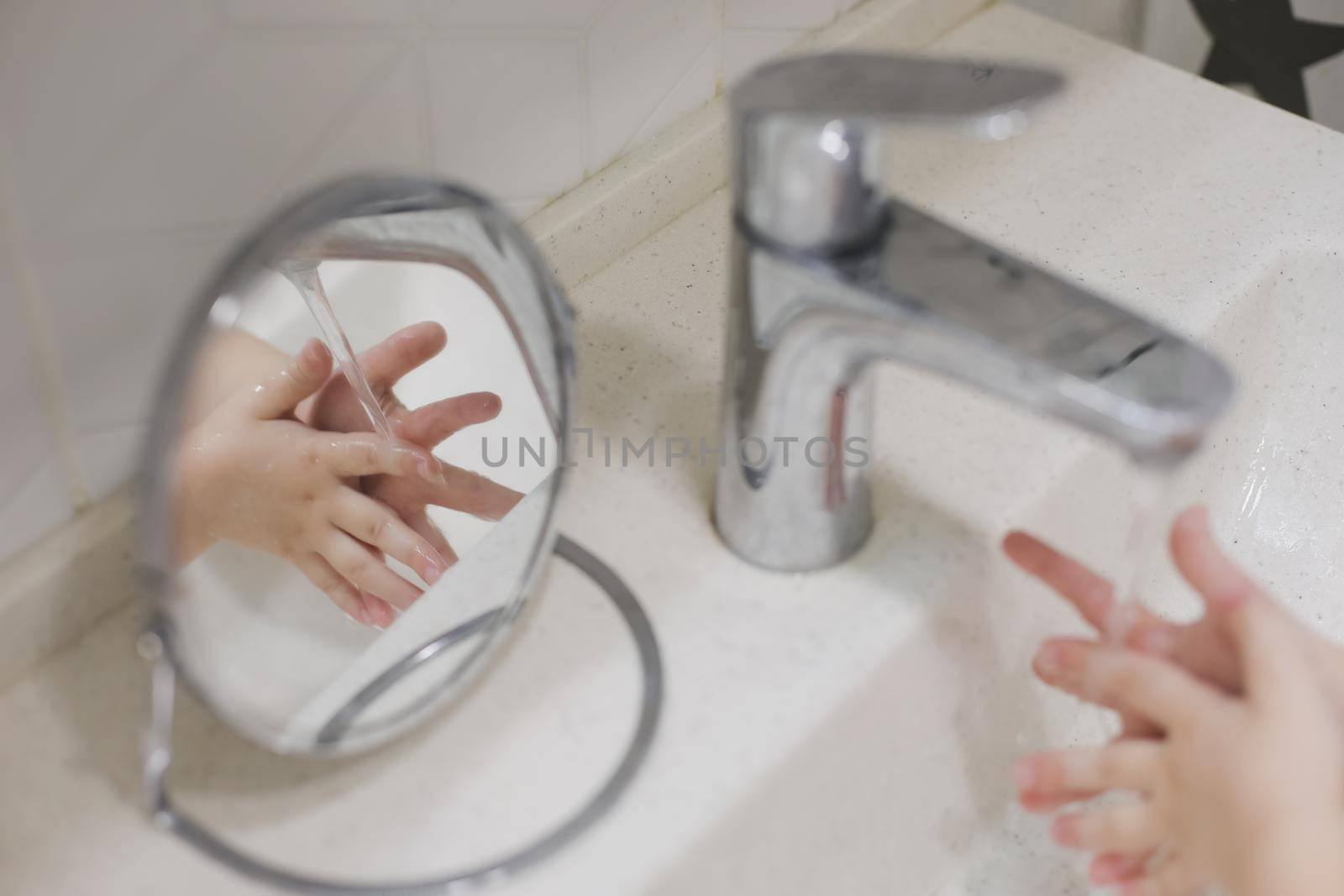 child washing hands under the tap water in the bathroom. kid's hands under stream of water.