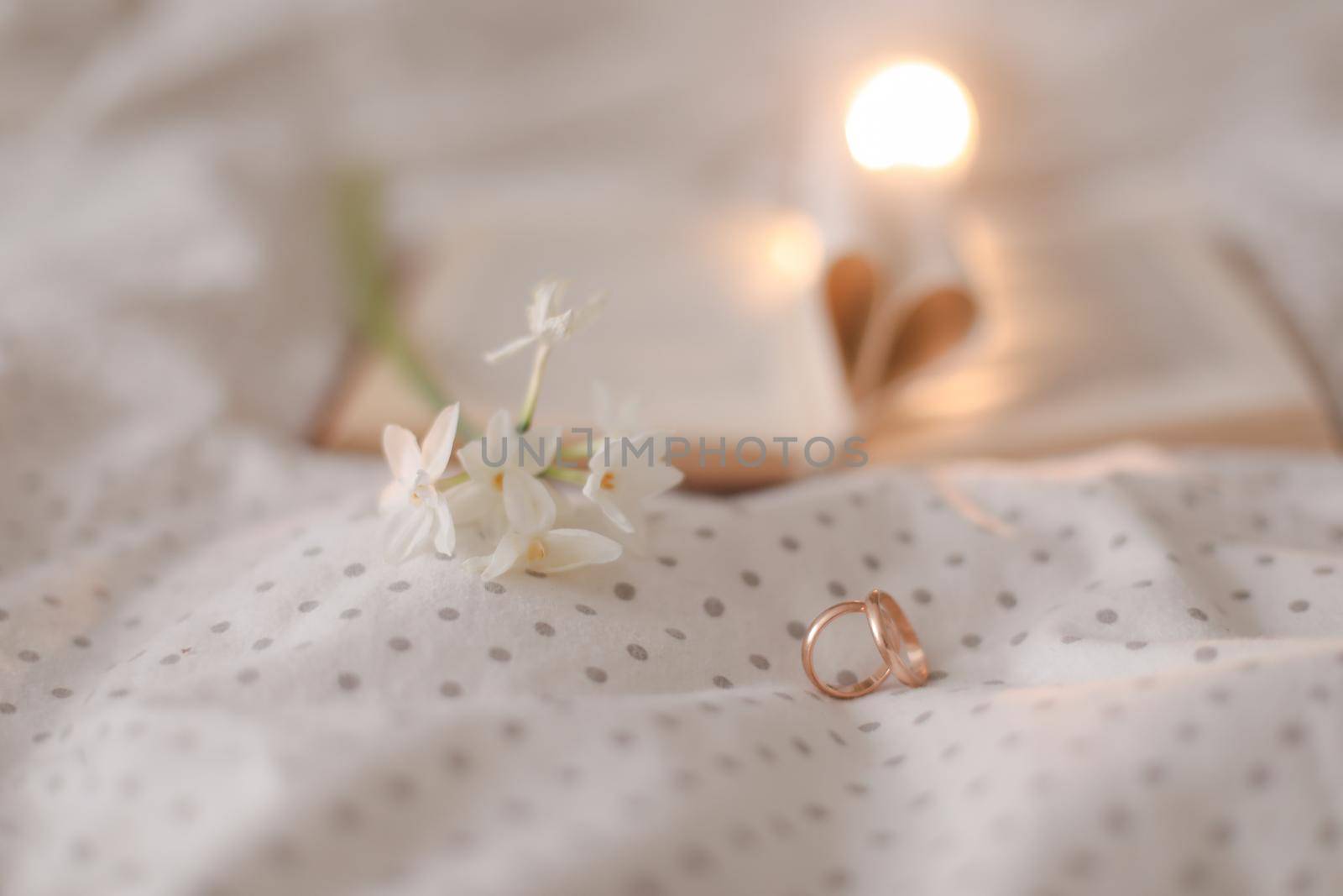 Golden ring and open book with folded sheets in heart shape in bed. Wedding concept, Happy Valentine's Day.