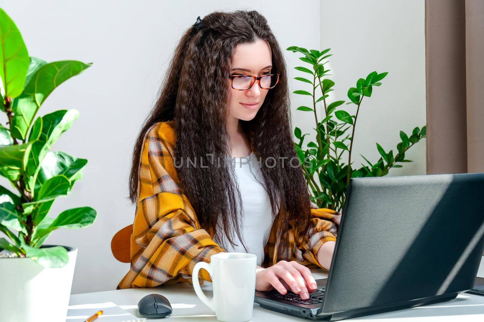 Focused woman in glasses typing on laptop keyboard is working at home, writing emails, online shopping or watching videos.